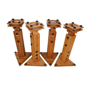 Four JamRacks Grand Stand speaker stands, carbonized wood with black hardware, geometric bases, and circular side holes, angled outward.