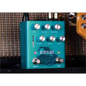 Teal Eventide Riptide guitar pedal with silver Vibe, Speed, Intensity, Drive, Tone, and Level knobs sits by an amp and guitar.