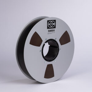 RTM SM911 R34420 2 NAB precision reel with silver metal spool and brown tape, set on a plain light background.