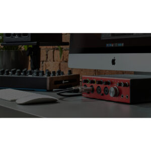 Modern desktop studio with an iMac, keyboard, MIDI controller, and Focusrite Clarett+ 4Pre USB interface on a gray table.