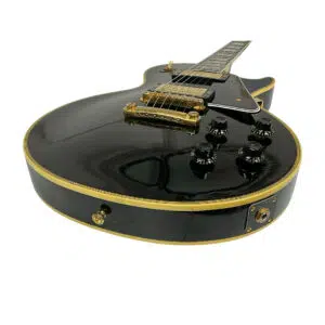 Preowned Gibson Custom 1957 Les Paul Reissue electric guitar, gold hardware, black knobs, cream binding, low angle view.