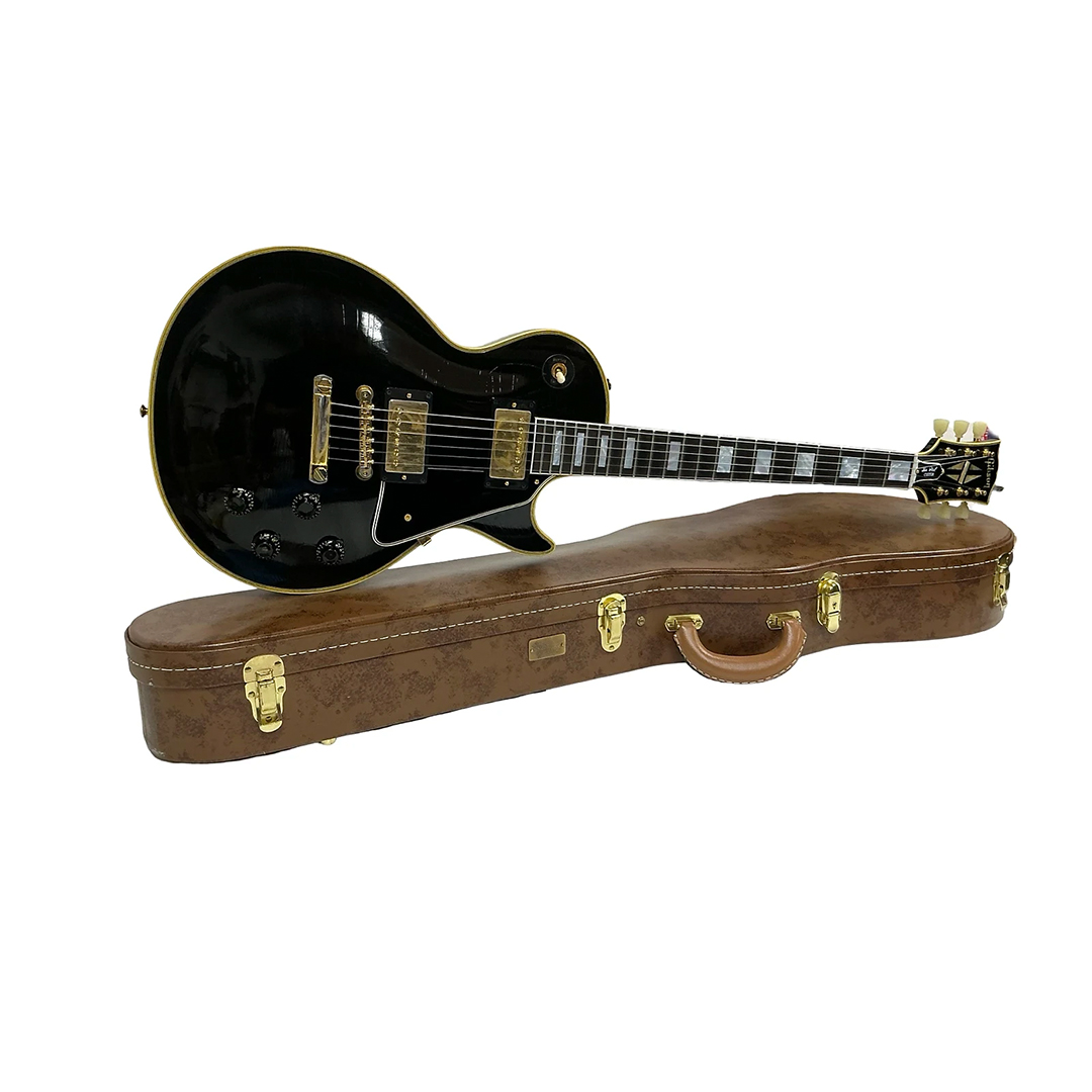 Preowned Gibson Custom 1957 Les Paul Reissue, black with gold hardware, on brown hardshell case, white background.