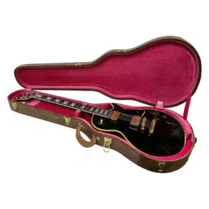 Preowned Gibson Custom 1957 Les Paul Reissue in black with gold hardware, in open brown pink-lined case on white background.