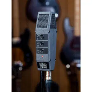 Milab VIP-60 condenser mic with control switches on stand; blurred guitars hang on wood wall in background.