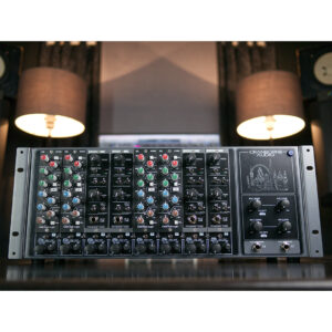 Cranborne 500ADAT rackmount module with colorful knobs on mixing console in pro studio, speakers and lamps behind.