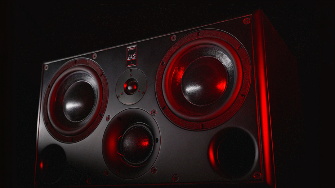 ATC SCM45A Pro studio monitor with dual woofers and tweeters, showcased in dramatic red lighting against a dark backdrop.