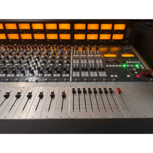 Rupert Neve Designs 5088 Console SN 0251 preowned, close-up of lit VU meters, knobs, sliders, and red fader for audio control.