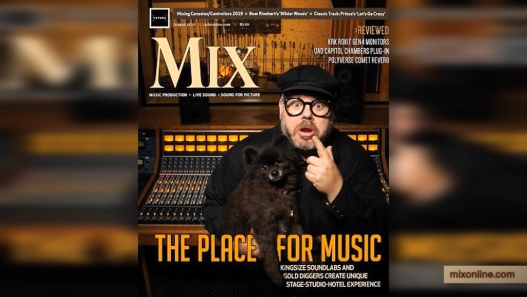 Man in glasses and hat holds small black dog in Kingsize Soundlabs studio, surrounded by audio gear; Mix magazine cover visible.
